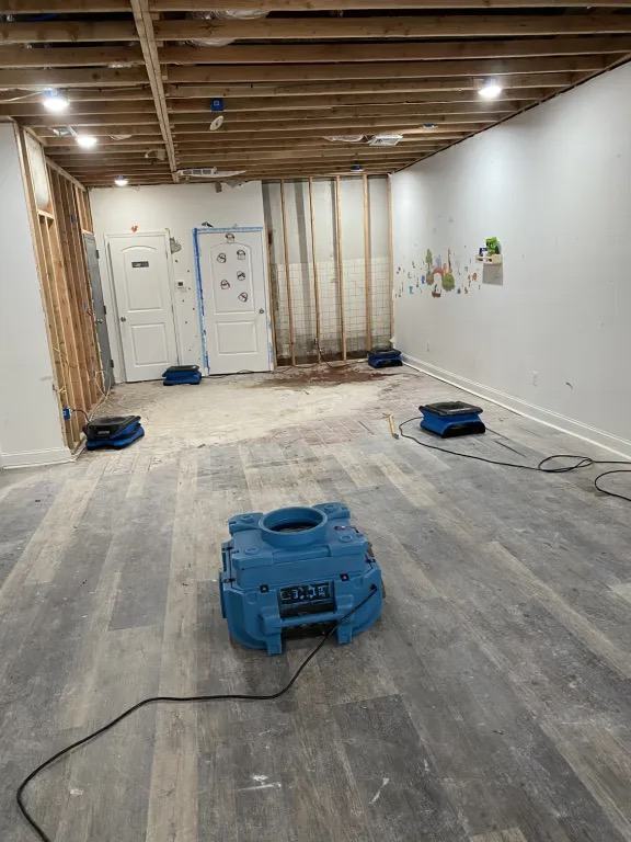 The same room from the opposite side, with a large blue machine in the foreground and air movers along the walls.